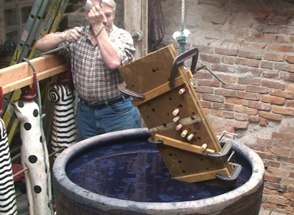 board-clamped fabric is lowered into the dye vat